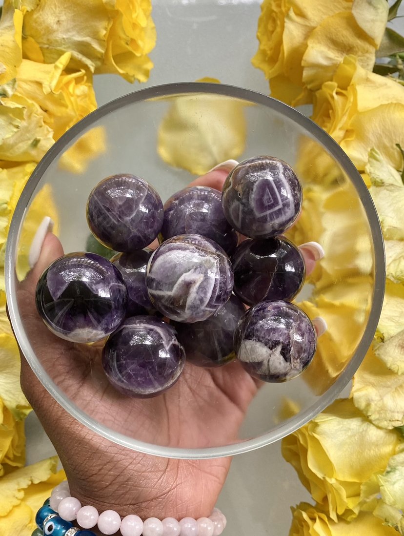 Amethyst works to relieves our minds of worry, stress, or tension. Amethyst helps to remove any mental distractions or clutter. Pictured are Chevron Amethyst Spheres in a bowl.